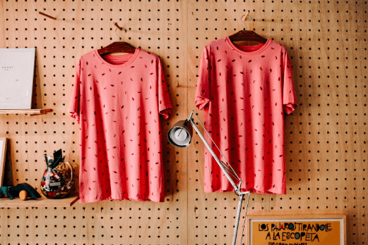Two pink patterned shirts hang next to each other on a wall
