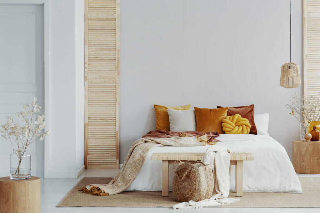 A bedroom is shown with a tasteful mix of white, warm and natural wood tones.