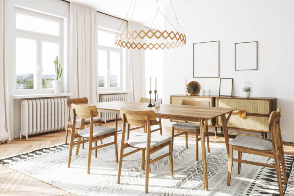 A wooden dining room set sits atop a chevron-patterned rug, with a modern wood-toned chandelier hanging overhead.