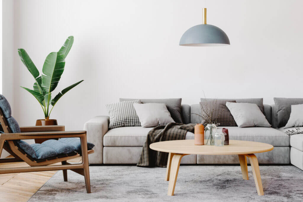 A living room is pictured with neutral tones, featuring simple, modern furniture.