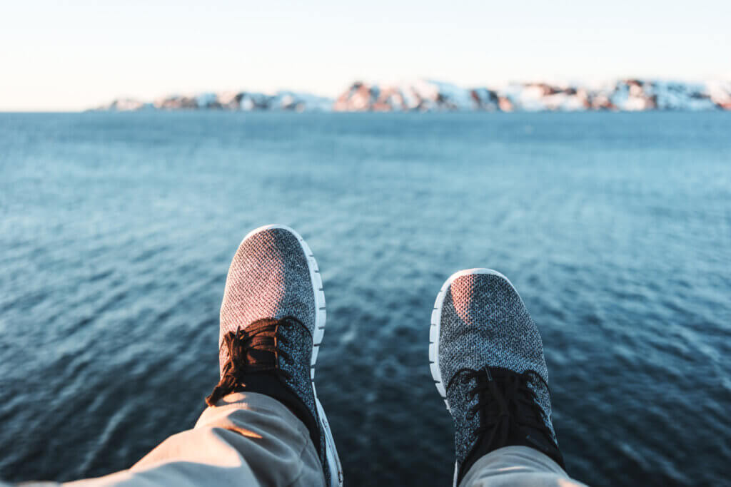 A person's feet — in shoes — are pictured hanging above a body of water.